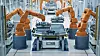 Modern Electric Car Automated Smart Factory. EV Battery Pack Production Line Equipped with Orange Advanced Robot Arms. Row of Robotic Arms inside Bright Plant Assemble Battery for Automotive Industry