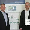 Ekkehard Brümmer und Martin Ruskowski stehen vor einem Werbebanner