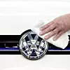 VW-Logo wird am Auto poliert.