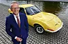 Opel-Chef Karl-Thomas Neumann ist auf dem Bild zu sehen. Im Hintergrund ein gelber Opel-Oldtimer.