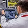 Ein Mitarbeiter von Porsche kontrolliert Bolzen mit Hilfe eines Tablets.