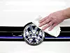 VW-Logo wird am Auto poliert.