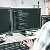 Ein Mitarbeiter von EDAG sitzt vor einem PC und blickt auf einen Code