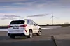 Die Heckansicht des BMW iX5 Hydrogen vor Windrädern. Grünstrom ist essenziell für den Nutzen der Brennstoffzelle.
