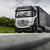Der Mercedes-Benz GenH2 Truck auf einer Straße hinter einer Leitplanke.