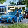 Ein blauer BMW X1 xDrive25e steht an einer Ladesäule vor dem Werkseingang des BMW Group Werks Regensburg.