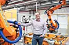 Benedikt Meier steht an einem Roboter im Audi-Werk