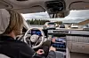 Eine Frau sitzt in einer S-Klasse von Mercedes-Benz und schaltet im Infotainment den autonomen Stau-Piloten auf Autobahnen ein.