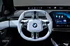 Innenansicht eines BMW i3 mit weißem Multifunktionslenkrad und großem Digitaldisplay.