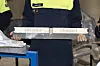 Worker in Volvo uniform holding a long aluminium casting sample in a factory.