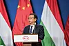Mann am Rednerpult mit BYD-Logo vor roten, weißen, schwarzen und grünen Flaggen.