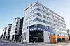 Modernes mehrstöckiges Bürogebäude mit Glasfassade an einer Straßenecke.