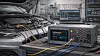 GÖPEL electronic MagicCAR compact plus Desktop-Testplattform für Automotive-Steuergeräte im Einsatz in einer Entwicklungsumgebung. Das kompakte Auftisch-Testsystem ist über mehrere Kabel mit einem Fahrzeug verbunden und unterstützt die Entwicklung, Validierung und Fehlersuche an modernen Steuergeräten. Es bietet Restbussimulation, Diagnose, programmierbare Spannungsversorgung, Strommessung sowie Unterstützung für CAN-FD, LIN, FlexRay, Automotive Ethernet und Secure Onboard Communication (SecOC). Im Hintergrund sind Messrechner und Testsysteme zur Analyse von Kommunikationsdaten und Fahrzeugnetzwerken zu sehen. Die Plattform eignet sich für Netzwerktests, Infotainment-Tests, Funktions-, Qualitäts- und Dauerlauftests von ECUs und Domänencontrollern in der Automobilentwicklung.