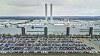 Luftaufnahme des Volkswagen-Werks in Zwickau mit großen Produktionshallen, zwei Schornsteinen und einem weitläufigen Parkplatz voller Fahrzeuge.