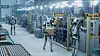 Automatisierte Fertigungshalle mit humanoiden Robotern, Maschinen und Fördertechnik.