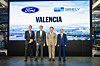 Vier Vertreter von Ford und Geely stehen in einer Produktionshalle vor einer großformatigen Anzeige mit den Logos beider Unternehmen und dem Schriftzug „Valencia“.