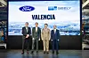 Vier Vertreter von Ford und Geely stehen in einer Produktionshalle vor einer großformatigen Anzeige mit den Logos beider Unternehmen und dem Schriftzug „Valencia“.
