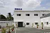 Weißes Firmengebäude mit MAHLE-Logo auf gepflastertem Hof mit Pflanzen.