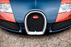 Frontansicht eines Bugatti mit typischem Kühlergrill und Logo auf gepflastertem Boden.