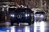 Zwei BMW X5 fahren in einer hellen Produktionshalle auf einer nassen Montagefläche.