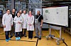 Mitarbeitende von Aumovio im Frankfurter Werk vor einem Bildschirm mit dem Virtual Line Information Board zur digitalen Steuerung von Produktionsprozessen.