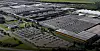 Luftansicht eines großen Industrieareals mit Hallen, Parkplätzen und Straßen.