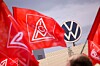 Rote IG-Metall-Fahnen vor einem Volkswagen-Logo auf einem Gebäude.
