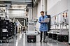 Autonome Transportroboter in einer Industriehalle, daneben ein Mitarbeiter mit Tablet.