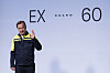 Ein Volvo-Mitarbeiter steht vor einer Wand mit der Aufschrift EX60 und Volvo beim Produktionsstart.