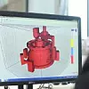 Ein Mitarbeiter von Voxeljet fertigt ein Antriebsteil am Monitor und bereitet es damit für den 3D-Druck vor.