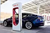 Ein Tesla steht neben einer Ladesäule.