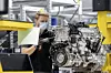 Ein Daimler-Mitarbeiter arbeitet an einem Motor.