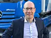 Portrait von Andreas Bachhofer vor einem blauen LKw von Daimler Trucks.