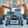 Modern Electric Car Automated Smart Factory. EV Battery Pack Production Line Equipped with Orange Advanced Robot Arms. Row of Robotic Arms inside Bright Plant Assemble Battery for Automotive Industry