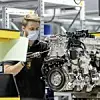 Ein Daimler-Mitarbeiter arbeitet an einem Motor.